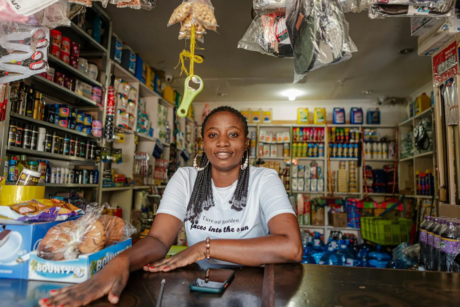 A shop owner smiling behind the counter of her well-stocked shop